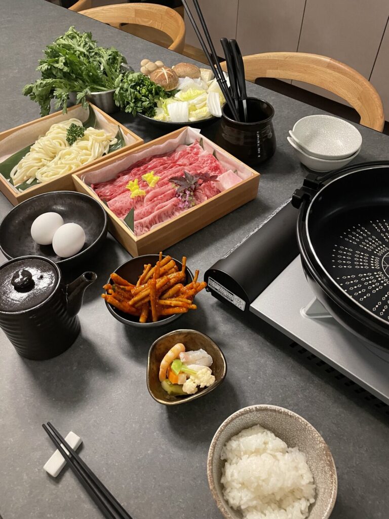肉・野菜・うどん・卵・ご飯が並ぶ客室の鍋セット